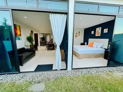 a bedroom with a bed and a living room at Apto con 2BR Jardin y Parking Gratis Col Escalon in San Salvador