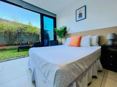 a bedroom with a large bed and a large window at Apto con 2BR Jardin y Parking Gratis Col Escalon in San Salvador