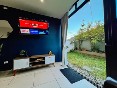 a living room with a tv on a blue wall at Apto con 2BR Jardin y Parking Gratis Col Escalon in San Salvador