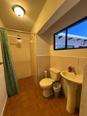 a bathroom with a toilet and a sink and a window at Neska Polita Hostel in Juayúa