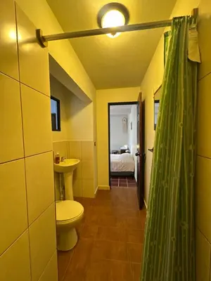 a bathroom with a toilet and a sink and a bed at Neska Polita Hostel in Juayúa