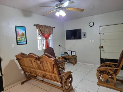 a living room with a wooden cart and a ceiling fan at La Casita Cruz in Caluco