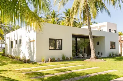 a white house with palm trees in front of it at Marcinco in Sonsonate