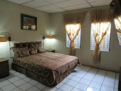 a bedroom with a large bed and two windows at casa de huéspedes lui in San Salvador