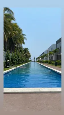 a large blue swimming pool with palm trees and buildings at Boa Mare in Nanastepeque