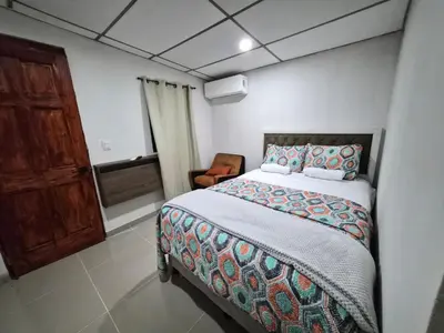 a bedroom with a bed and a chair at Ciudad Merliot, casa Don Pablo in Hacienda Plan de La Laguna