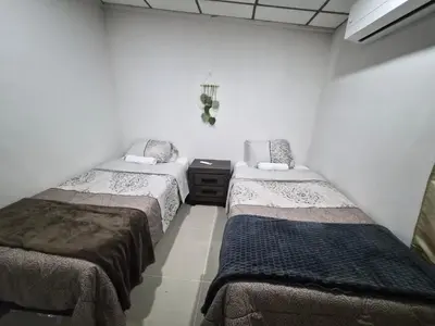 two twin beds in a room with white walls at Ciudad Merliot, casa Don Pablo in Hacienda Plan de La Laguna