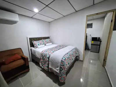 a bedroom with a bed and a chair in it at Ciudad Merliot, casa Don Pablo in Hacienda Plan de La Laguna