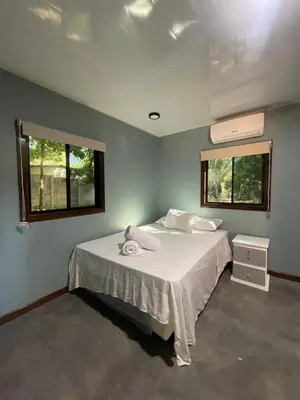 a bedroom with a bed and two windows at El Mangal del Zonte in El Zonte