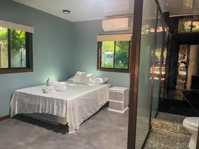 a bedroom with a bed and a glass shower at El Mangal del Zonte in El Zonte