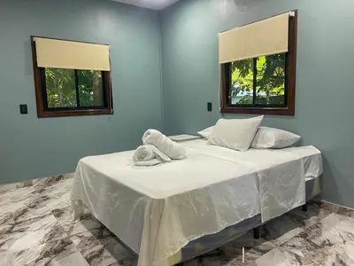 a blue bedroom with a bed with two windows at El Mangal del Zonte in El Zonte