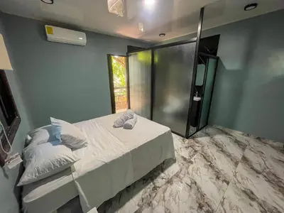 a bedroom with a bed and a glass shower at El Mangal del Zonte in El Zonte