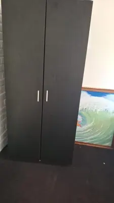 a black cabinet is standing next to a painting at Hostel Bella Luna in El Zonte