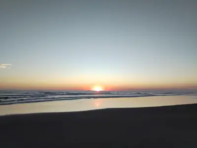 a sunset on a beach with the ocean at La Casita de la Playa La Bocana San Juan in Metalío
