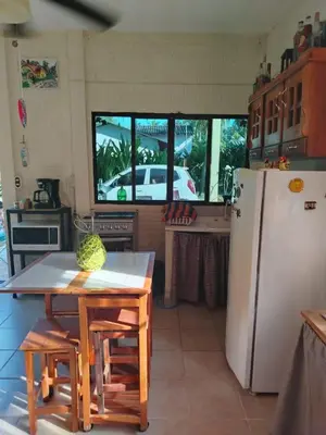 a kitchen with a table and a white refrigerator at La Casita de la Playa La Bocana San Juan in Metalío