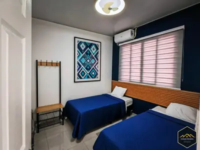 a room with two beds and a window with a blue bedspread at Casa Brisa Volcanica - Residencial Nueva San Miguel with AC in San Miguel