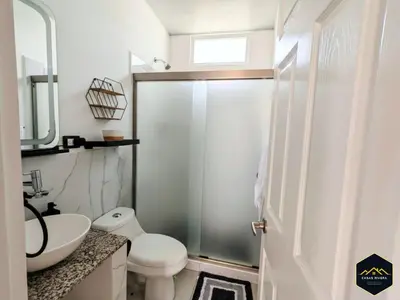 a bathroom with a white toilet and a sink at Casa Brisa Volcanica - Residencial Nueva San Miguel with AC in San Miguel