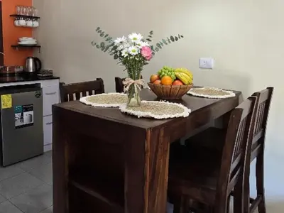 a wooden table with a bowl of fruit and a vase of flowers at Casa Juanita Juayua in Juayúa