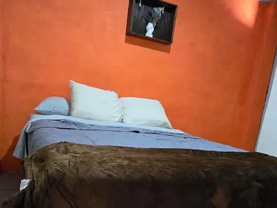 a bedroom with a bed with an orange wall at Casa Juanita Juayua in Juayúa