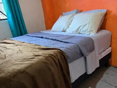 a bed with white sheets and pillows in a room at Casa Juanita Juayua in Juayúa