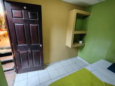 a room with a wooden door and a room with a bed at Rooms libertad in San Salvador