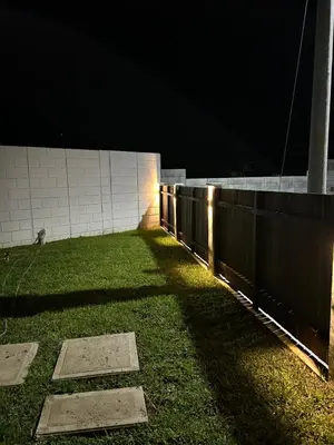 a fence with lights on the grass at night at Casa maea loma alta in Sonzacate