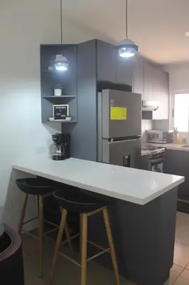 a kitchen with a counter and two bar stools at Casa maea loma alta in Sonzacate