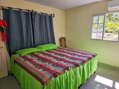a bedroom with a bed with a green comforter and a window at Honey Beach House in La Esmeralda