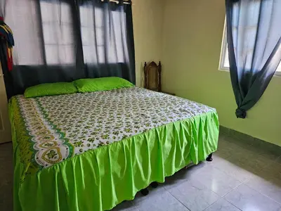 a bedroom with a bed with green sheets and a window at Honey Beach House in La Esmeralda