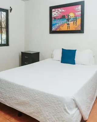 a bedroom with a large white bed with a picture on the wall at Papaya Lodge in La Libertad
