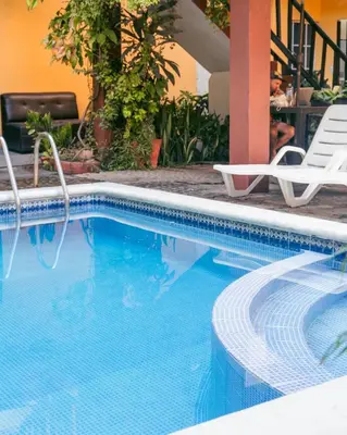 a swimming pool with two chairs next to a building at Papaya Lodge in La Libertad