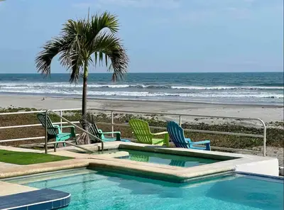 a swimming pool with chairs and a palm tree and the beach at House in Costa del Sol with beach access 5 bedrooms in Marcelino