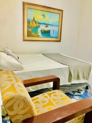 a bedroom with a bed and a chair and a painting at Hostal Los planes de Renderos