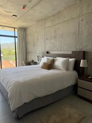 a bedroom with a large white bed with a large window at Apartamento en la mejor zona - San Benito ARTHAUS in San Salvador