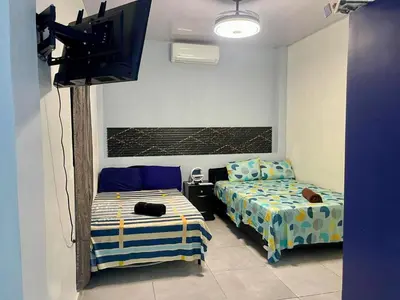 a room with two beds and a flat screen tv at Evolution Home Habitacion a 4 min del Aeropuerto Internacional ES in Las Flores
