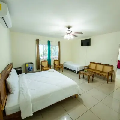a bedroom with a large white bed and a couch at Hotel y restaurante el faro resort in San Salvador