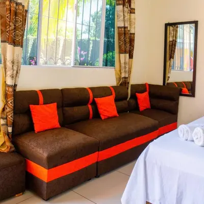 a brown couch with orange pillows in a room at Hotel y restaurante el faro resort in San Salvador