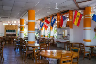 a restaurant with tables and chairs and flags on the walls at Hotel Pablo Tesák in San Vicente