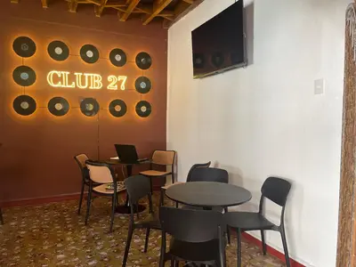 a dining room with tables and chairs and a tv at Club 27 - Hostal, Cafe & Spa in Santa Ana
