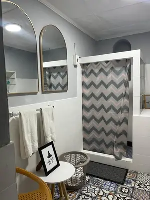 a bathroom with a shower curtain and a table and chairs at Club 27 - Hostal, Cafe & Spa in Santa Ana