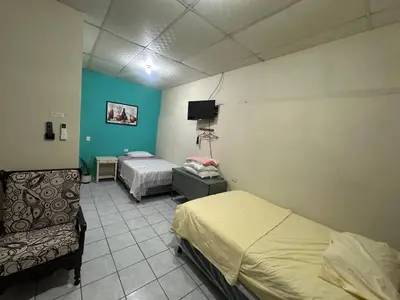 a room with two beds and a couch and a tv at Hostal las brisas in El Rosario
