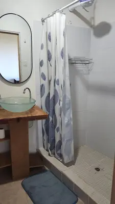 a bathroom with a sink and a shower curtain at Cabañas y Café Kauani