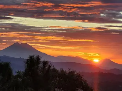 a sunset over a mountain range with the sun setting at Cabañas y Café Kauani