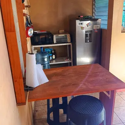 a kitchen with a wooden table and a refrigerator at Casa de Mango in Antiguo Cuscatlán