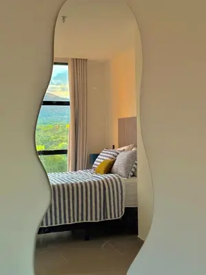 a mirror in a bedroom with a bed and a window at Cozy apartment in San Benito in San Salvador