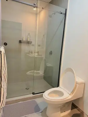 a bathroom with a toilet and a glass shower at Cozy apartment in San Benito in San Salvador