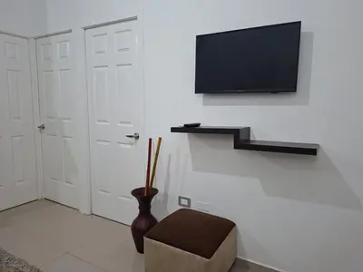 a room with a tv and a chair and a door at Nueva San Miguel - Casa Chaparrastique in San Miguel