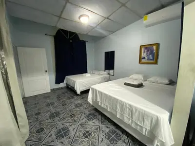 a room with two beds in a room with a door at Hostal Morales García in San Marcos