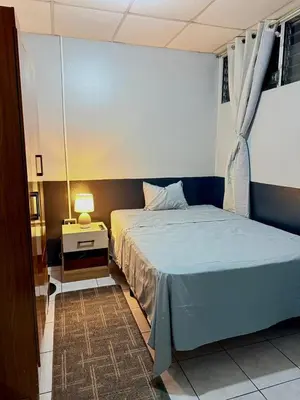 a bedroom with a blue bed and a night stand at Casa Armon - Frente a Estadio Cuscatlán in San Salvador