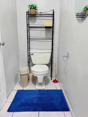 a bathroom with a toilet and a blue rug at Casa Armon - Frente a Estadio Cuscatlán in San Salvador